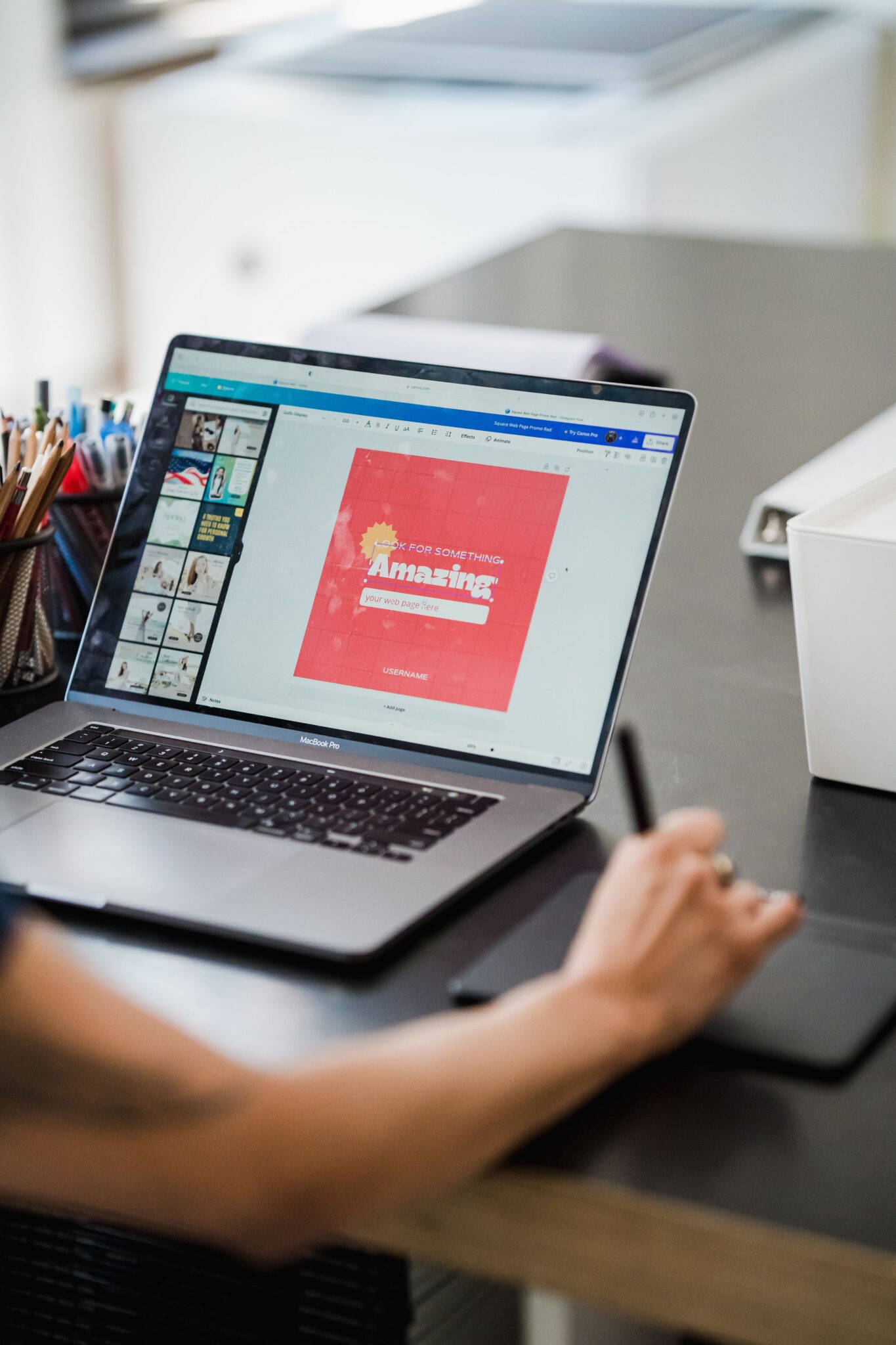 Person using a laptop and graphic tablet for digital design work in a home office.